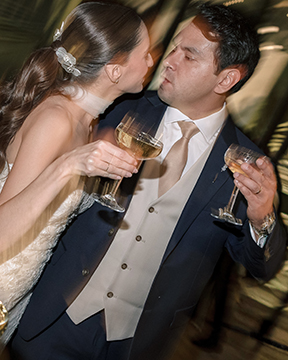 Candid documentary wedding moment — bride and groom sharing a kiss during reception, motion blur capturing the emotion of the night