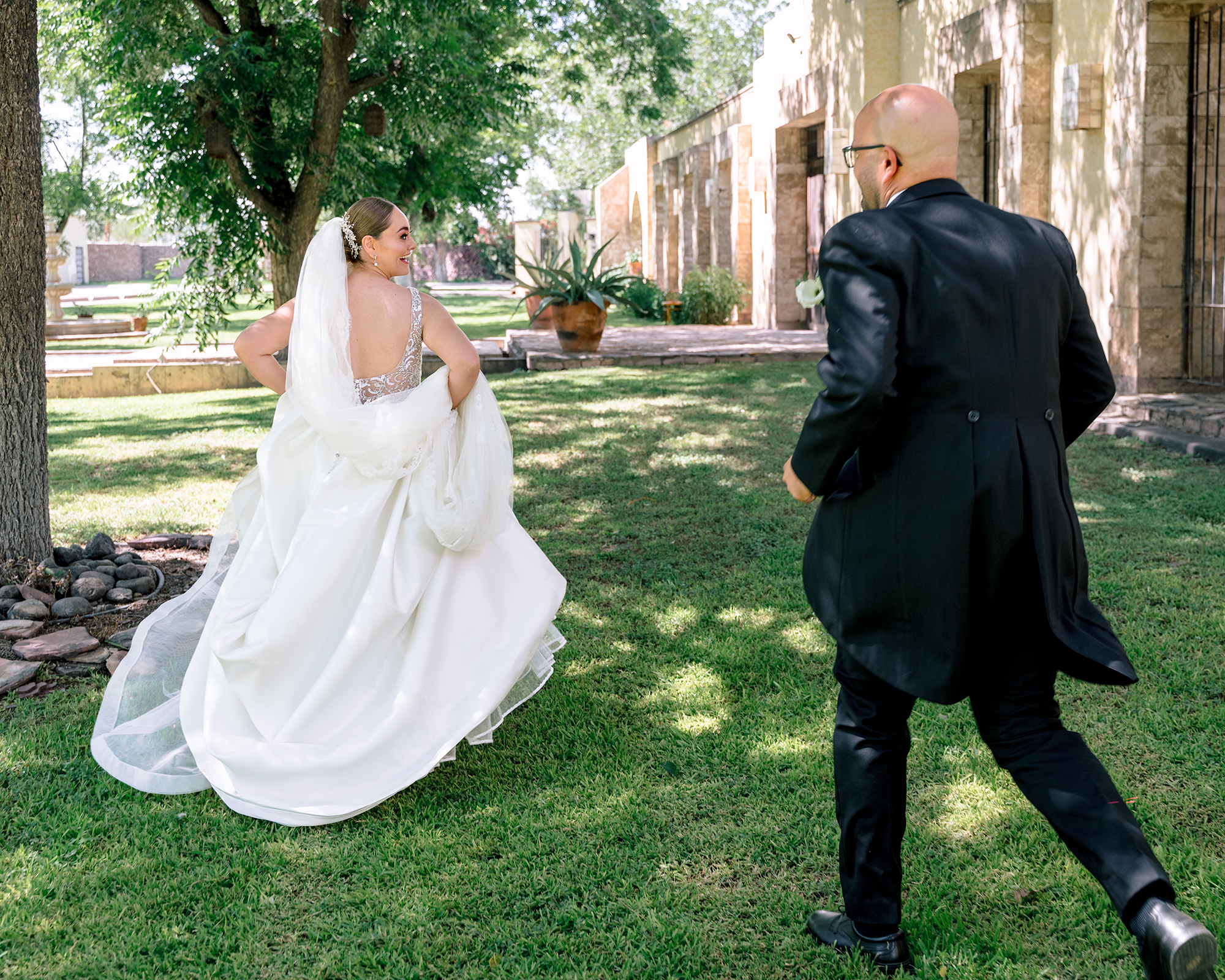 Candid first look wedding moment — bride turning toward groom in hacienda garden, natural and unposed
