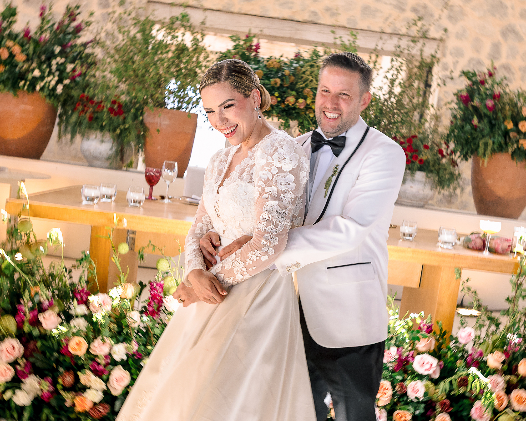 Candid wedding portrait — couple laughing together surrounded by flowers at San Miguel de Allende reception