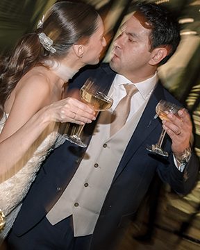 Candid documentary wedding moment — bride and groom sharing a kiss during reception, motion blur capturing the emotion of the night