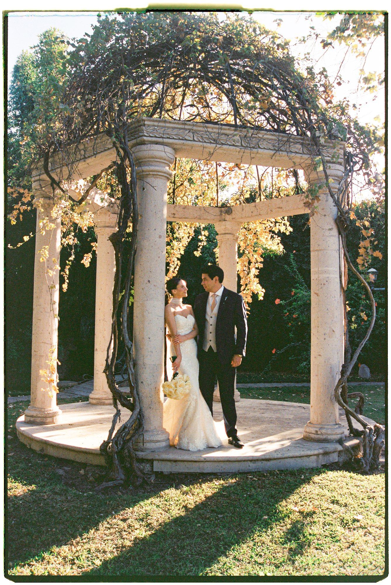Bride and groom under a stone gazebo at golden hour, photographed on 35mm film — David Lack