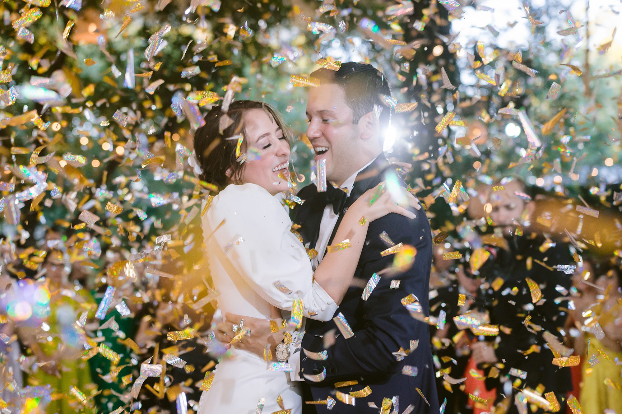 María y Gilberto riendo bajo una tormenta de confetti dorado en su boda en Coahuila